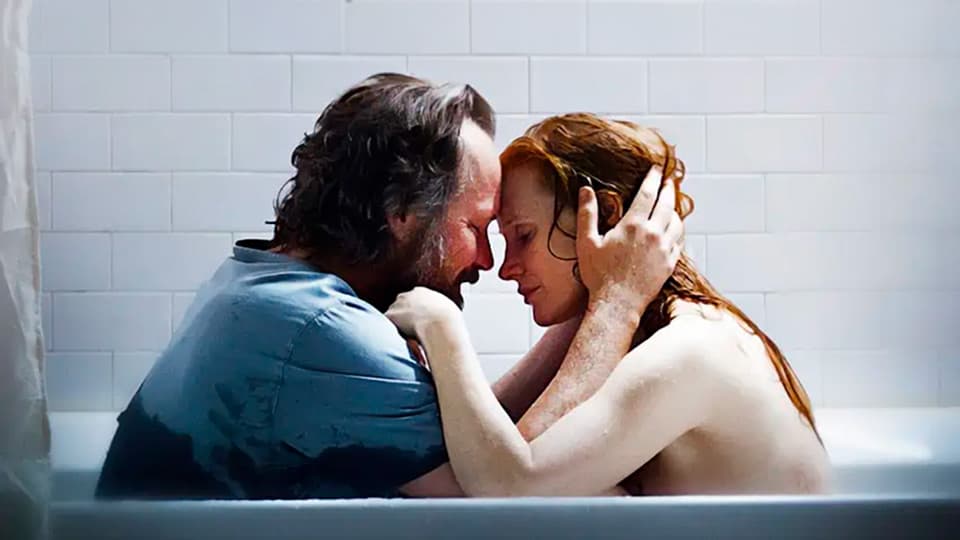Memory screenplay hero image with Jessica Chastain and Peter Sarsgaard sitting in a bathtub, holding each other closely, tenderly.
