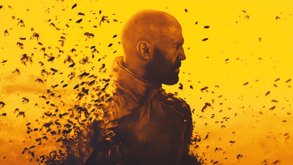 Image of a man surrounded by a swarm of bees from the movie The Beekeeper.